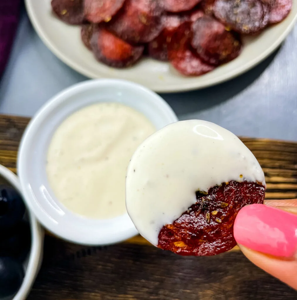 person holding pepperoni chip with ranch