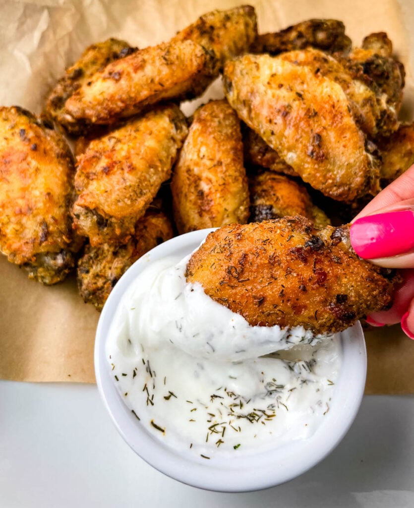 person holding ranch chicken wing dipped in ranch dressing