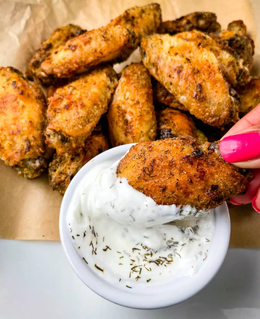 person holding ranch chicken wing dipped in ranch dressing