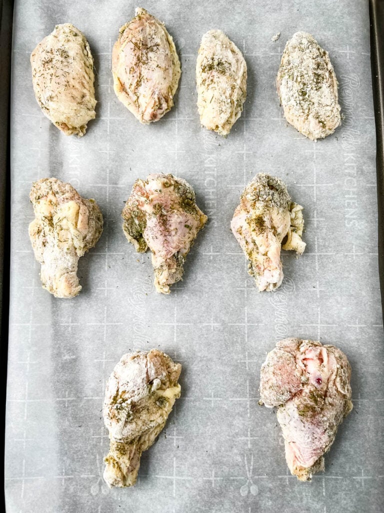 raw ranch chicken wings on a sheet pan with parchment paper