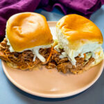 pulled pork sliders with coleslaw on a pink plate