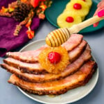 ham sliced on a plate with pineapples, cherries, and drizzled in honey