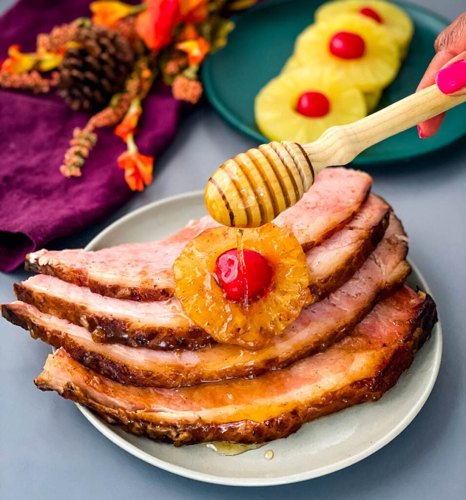 ham sliced on a plate with pineapples, cherries, and drizzled in honey