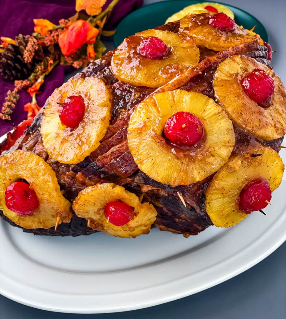 pineapple glazed ham with cherries on a white plate