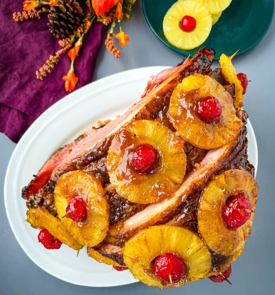 pineapple glazed ham with cherries on a white plate