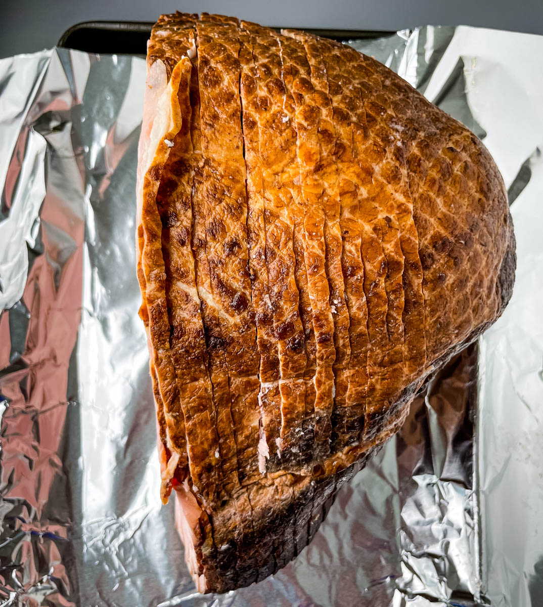 unbaked spiral sliced ham on foil and a sheet pan