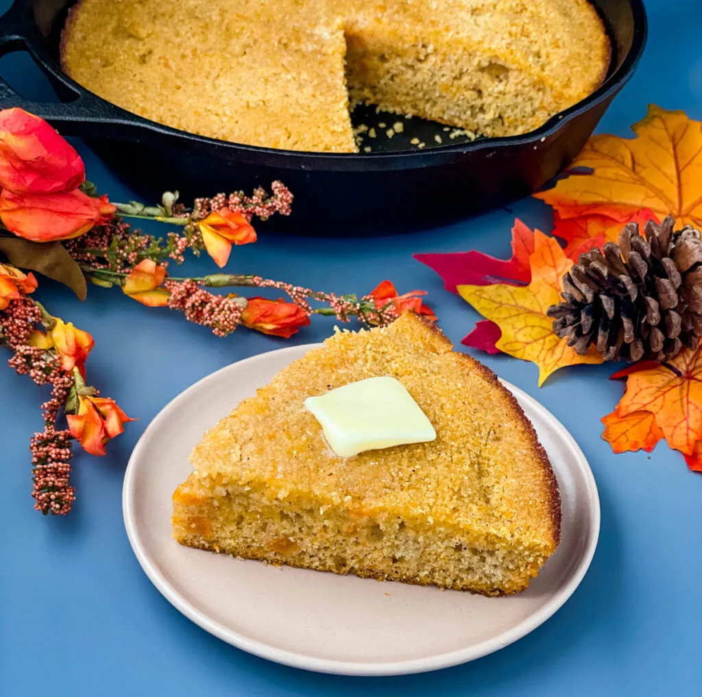 sweet potato cornbread on a plate with a skillet of cornbread