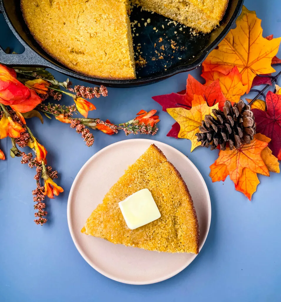 sweet potato cornbread on a plate with a skillet of cornbread