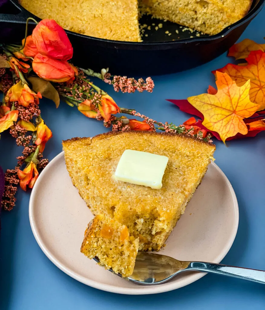 sweet potato cornbread on a plate with a skillet of cornbread