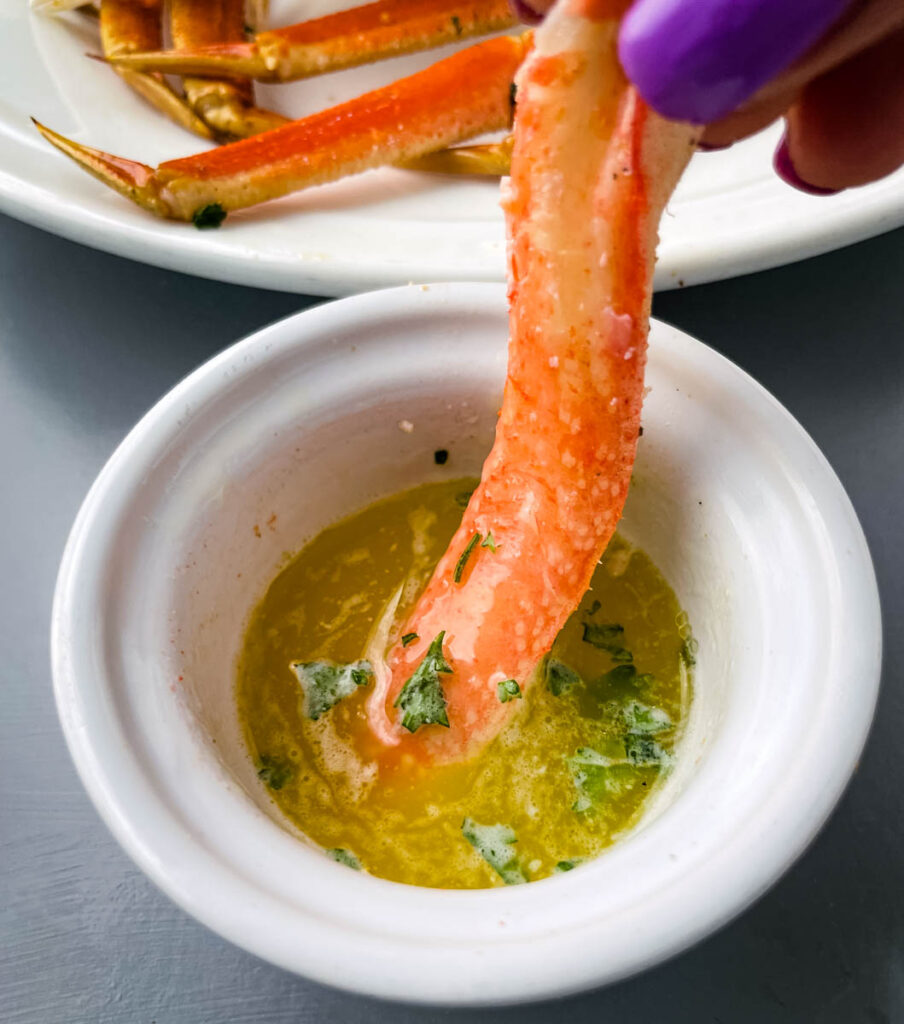 person holding crab leg meat dipped in butter