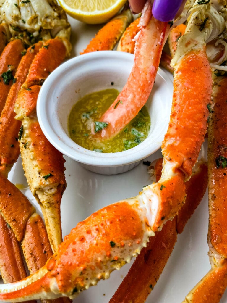 person holding crab leg meat dipped in butter