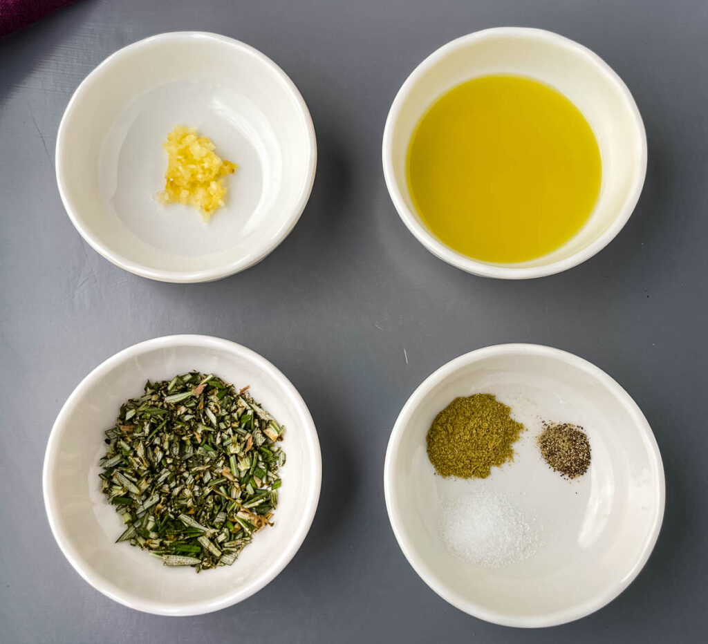 garlic, olive oil, rosemary, and oregano in white bowls