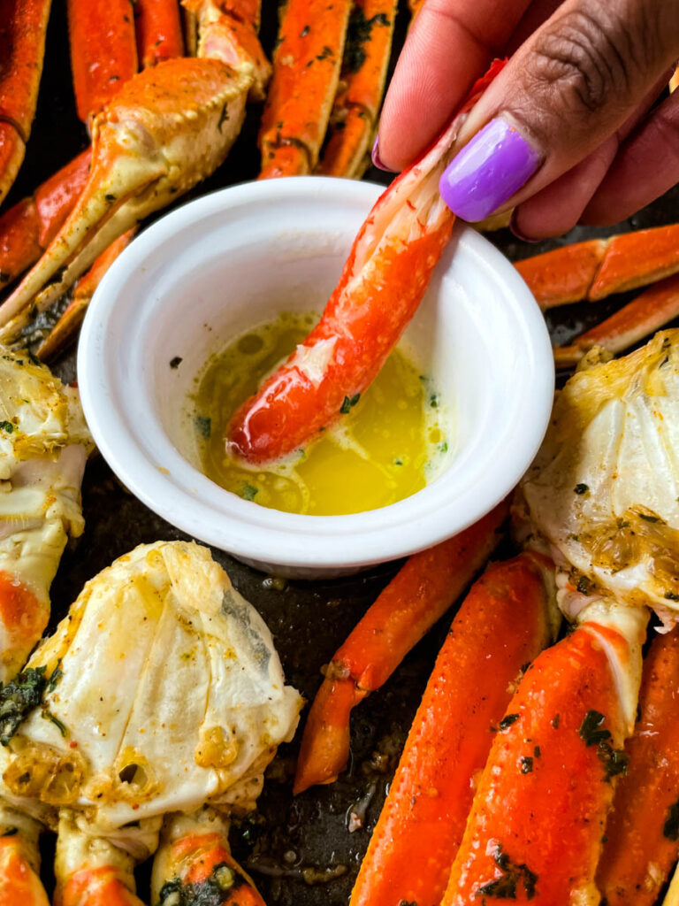 person holding crab leg meat dipped in butter