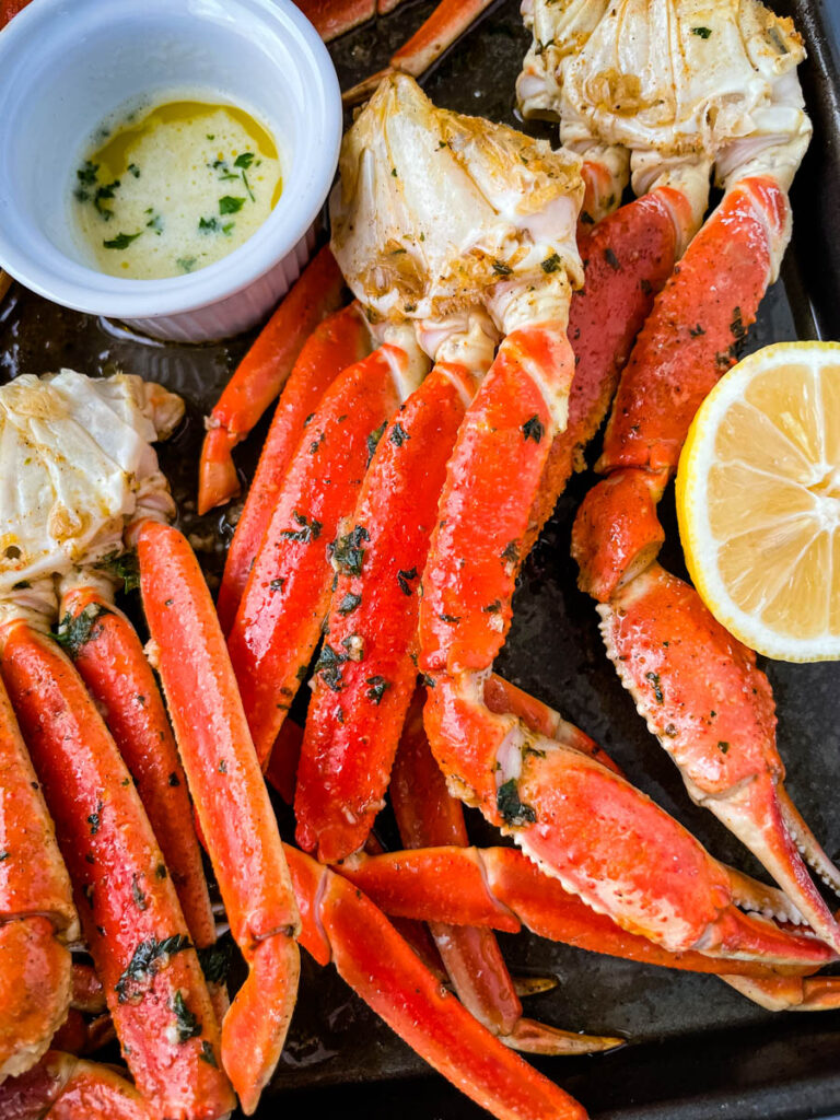 baked crab legs on a pan with lemon garlic butter