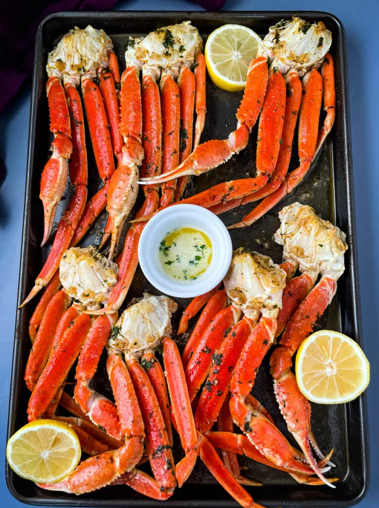 baked crab legs on a pan with lemon garlic butter