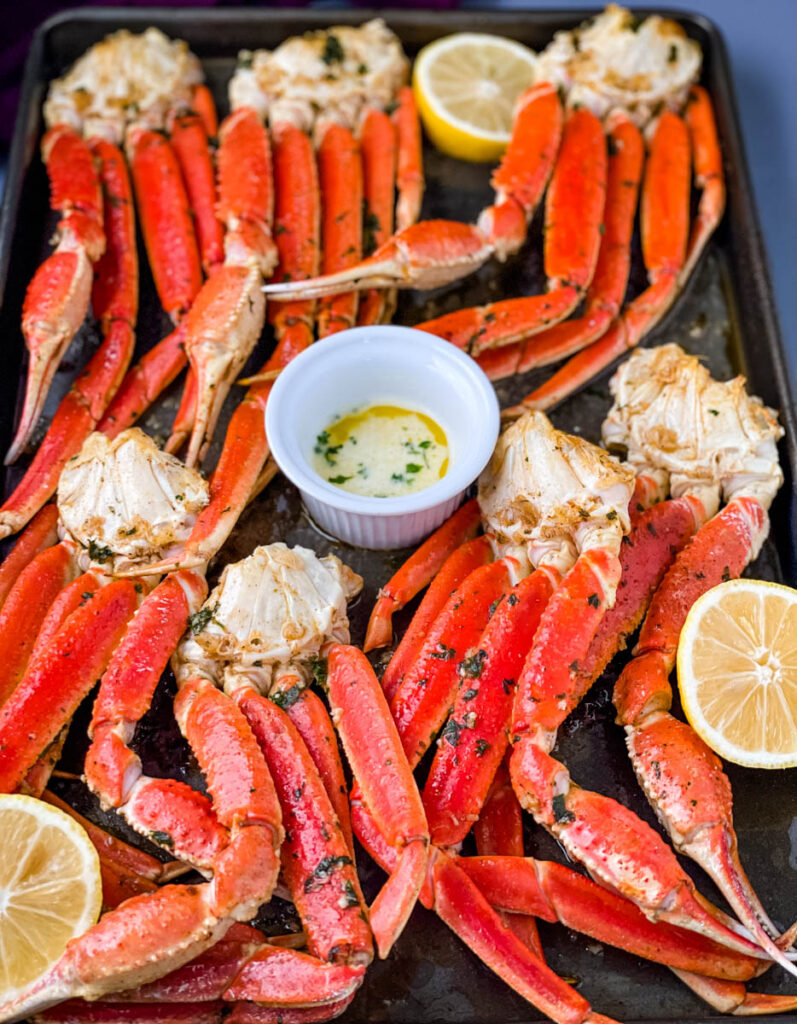 baked crab legs on a pan with lemon garlic butter