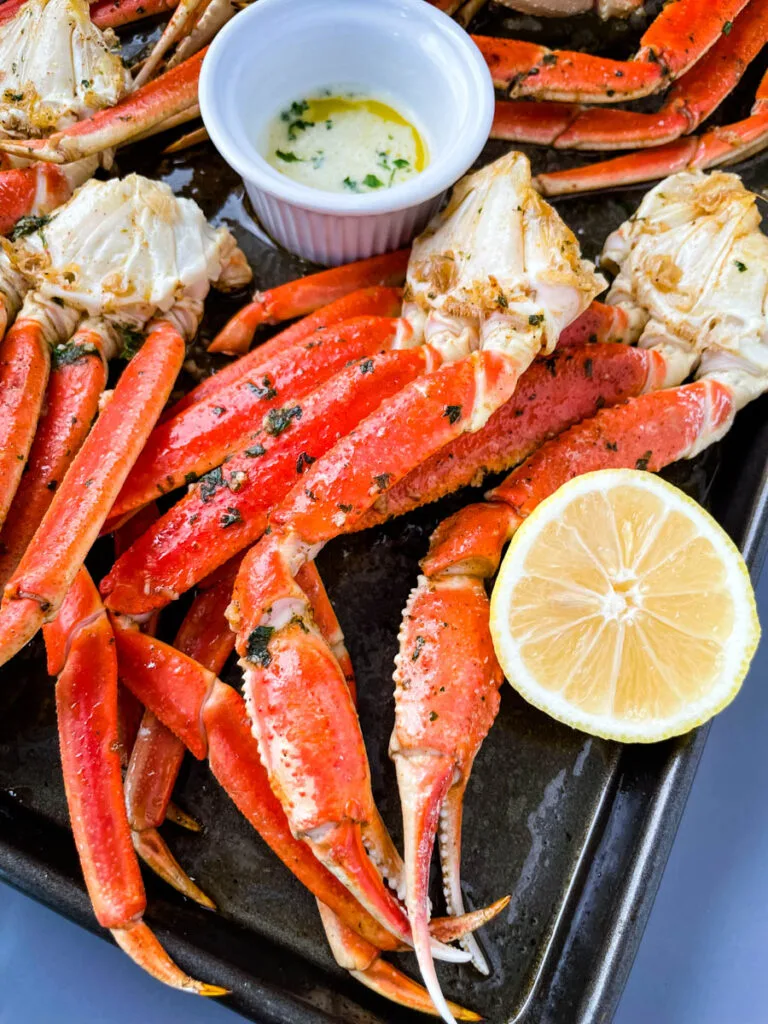 baked crab legs on a pan with lemon garlic butter