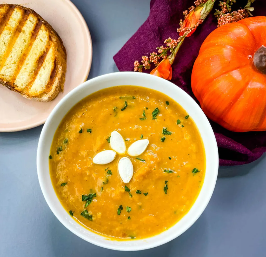 creamy canned pumpkin soup in a white bowl with a slice of bread