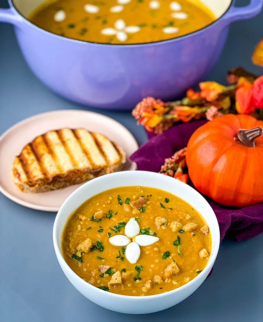 creamy canned pumpkin soup in a white bowl with a slice of bread