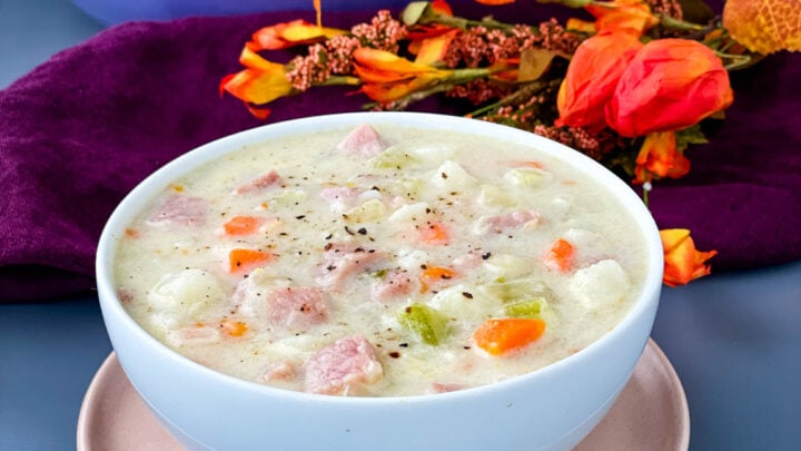 creamy ham, potato, and vegetable soup in a white bowl