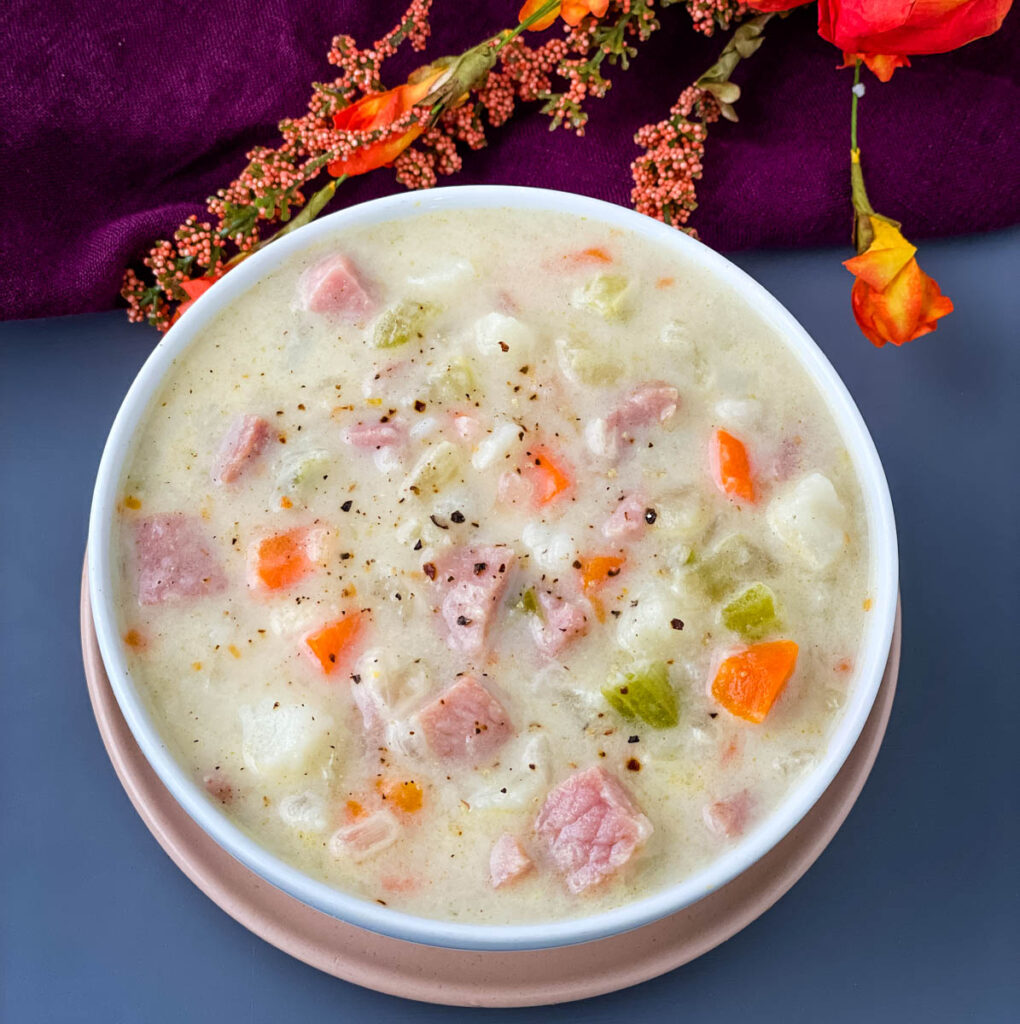 creamy ham, potato, and vegetable soup in a white bowl