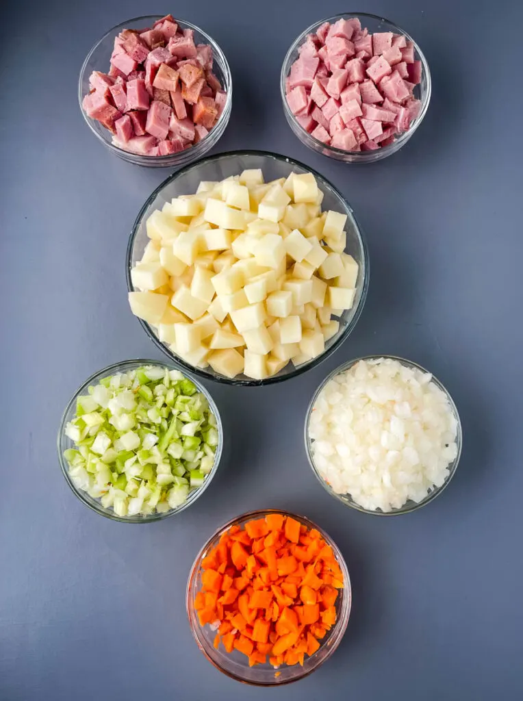 diced ham, diced potatoes, diced celery, diced carrots, and diced onions in separate glass bowls