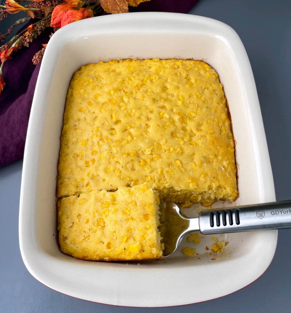 a slice of corn casserole in a baking dish