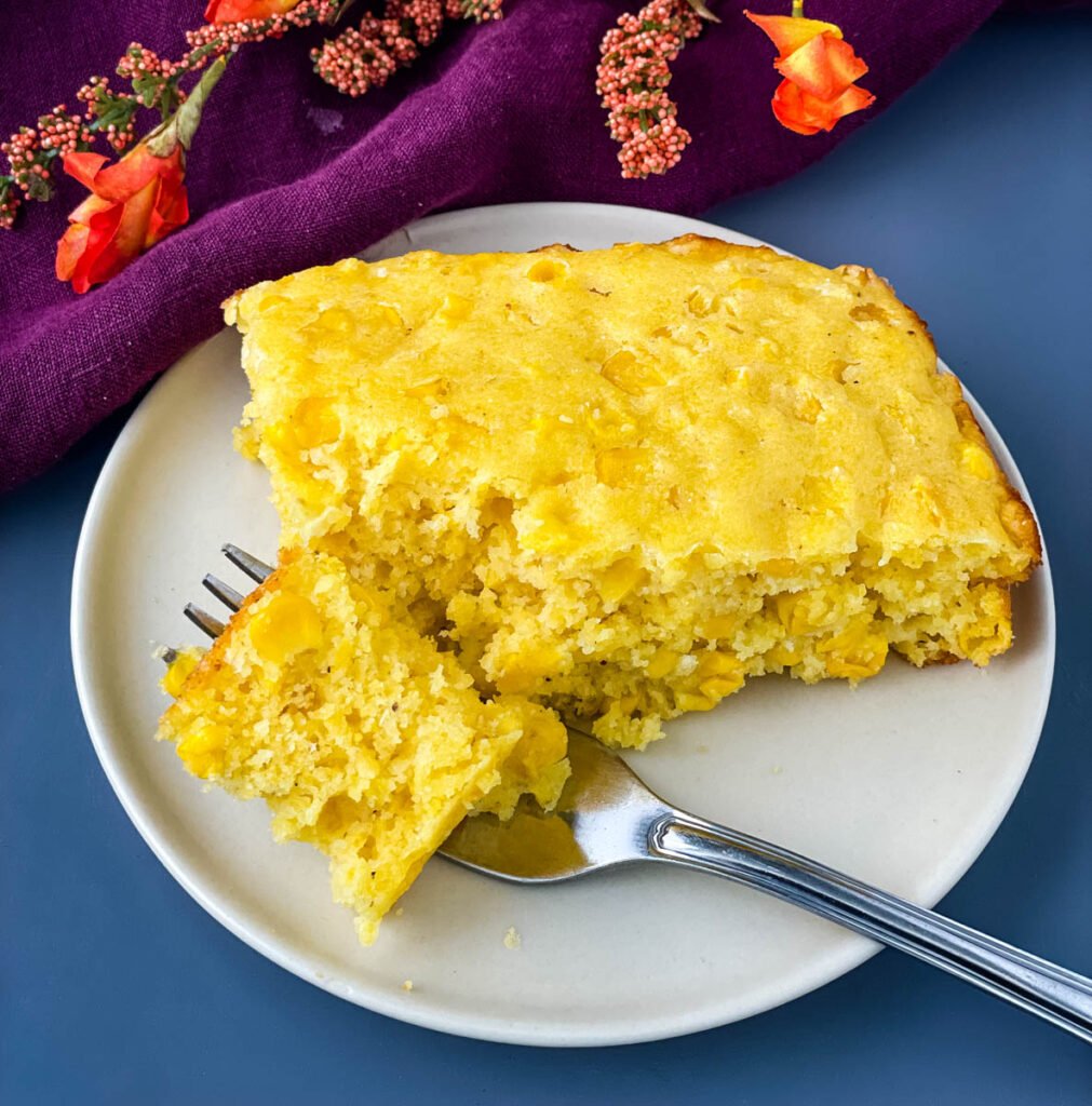 a forkful and slice of homemade cornbread casserole on a white plate