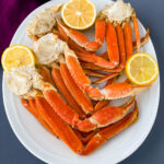 Instant Pot crab legs on a white plate with lemon