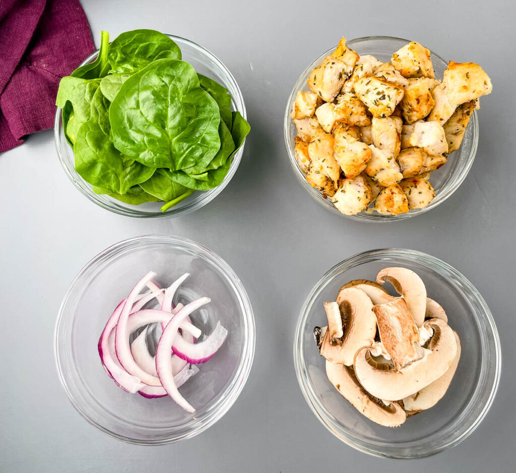 fresh spinach, onions, mushrooms, and cooked and cubed chicken breast in separate bowls