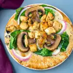 pita bread pizza with spinach, chicken, mushrooms, and onions