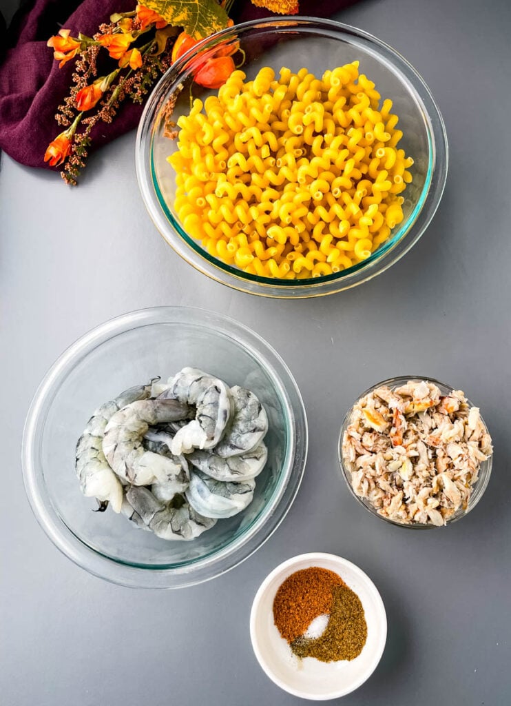 dry pasta, raw shrimp, crab, and spices in separate bowls