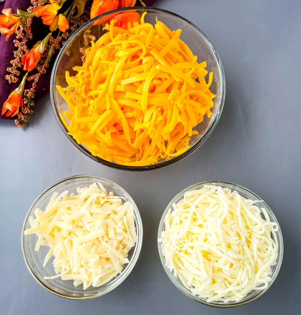 shredded cheddar cheese, mozzarella, and Parmesan cheese in glass bowls
