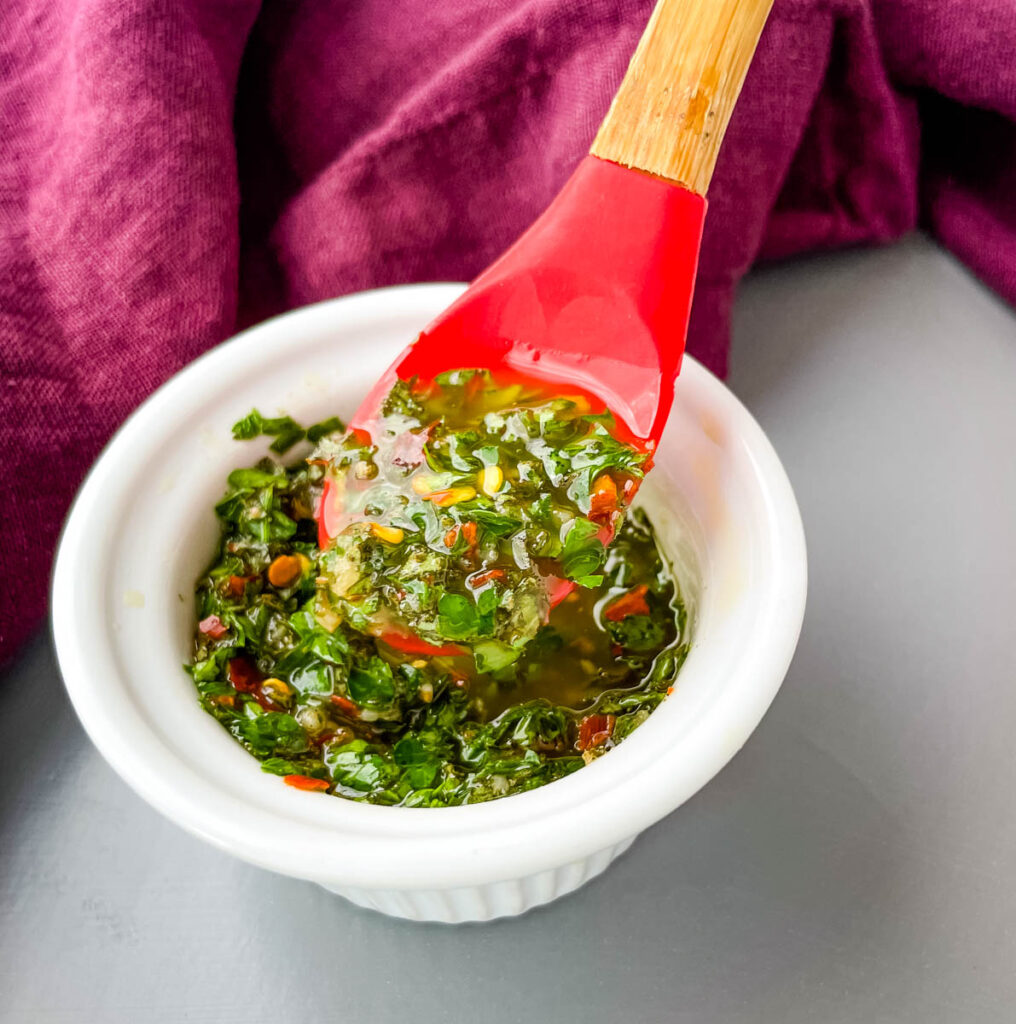 Chimichurri Sauce in a white bowl with a red spoon