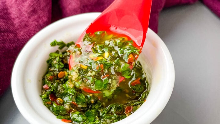 Chimichurri Sauce in a white bowl with a red spoon
