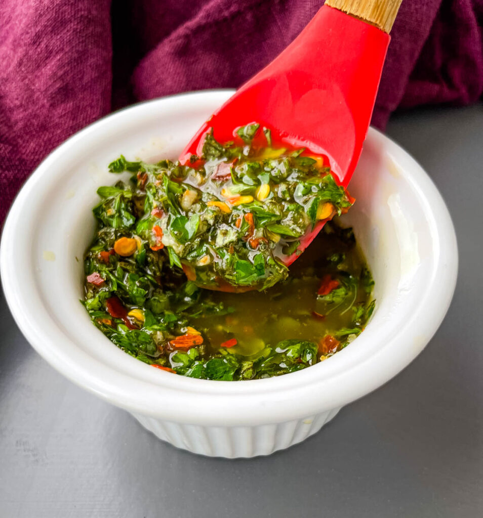 Chimichurri Sauce in a white bowl with a red spoon