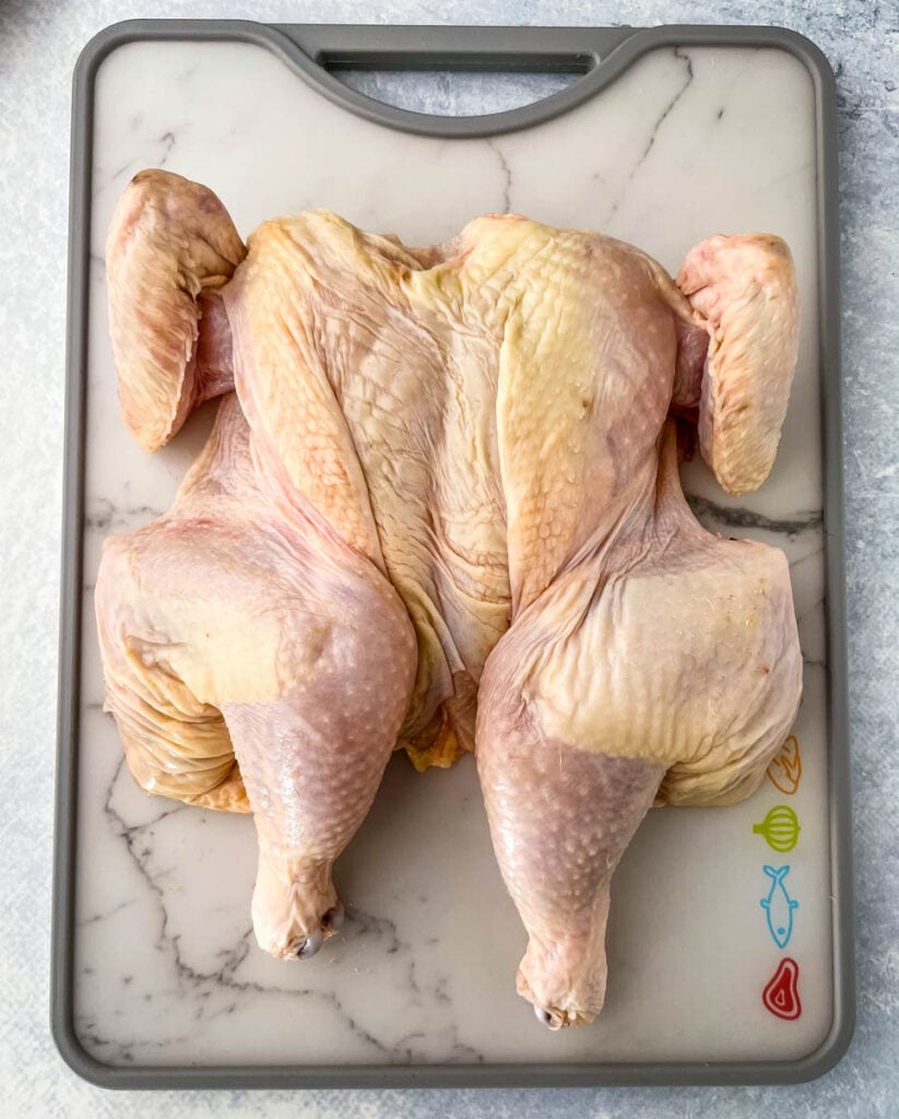 raw spatchcock chicken on a cutting board