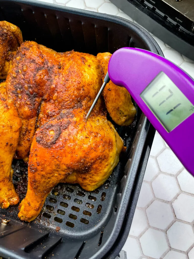 spatchcock chicken in air fryer with a meat thermometer showing 171 degrees