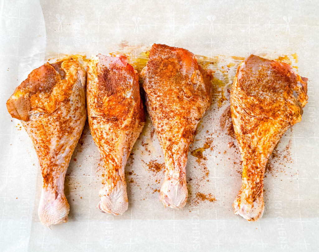 raw seasoned turkey legs on parchment paper