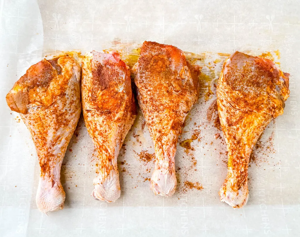 raw seasoned turkey legs on parchment paper