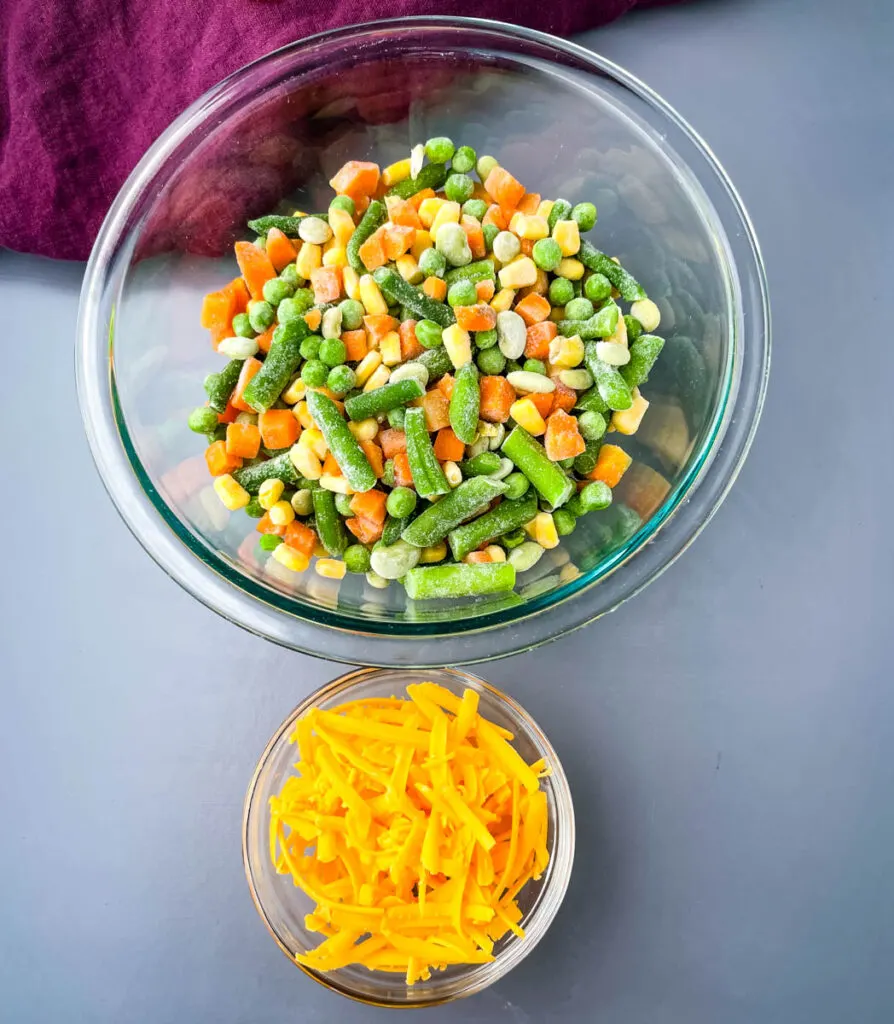 frozen mixed vegetables and shredded cheddar cheese in separate bowls