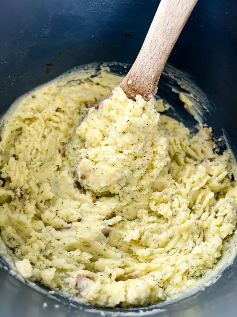 ranch mashed potatoes in a pot with a wooden spoon