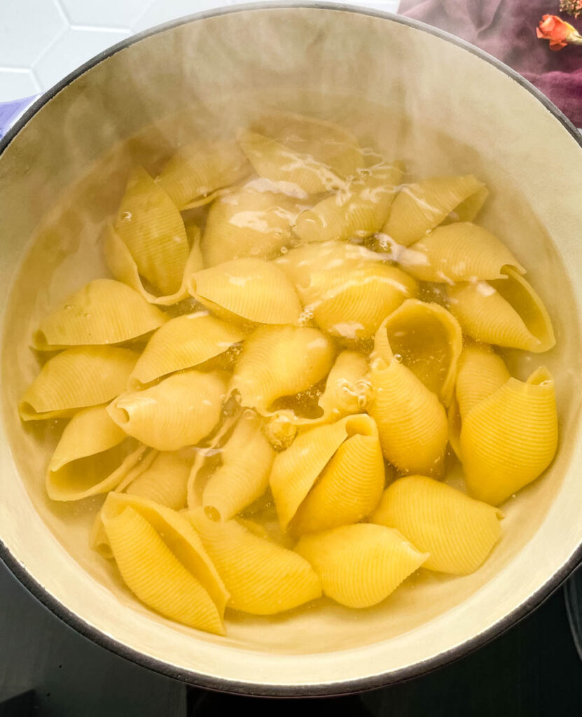 shells pasta cooking in water and a pot