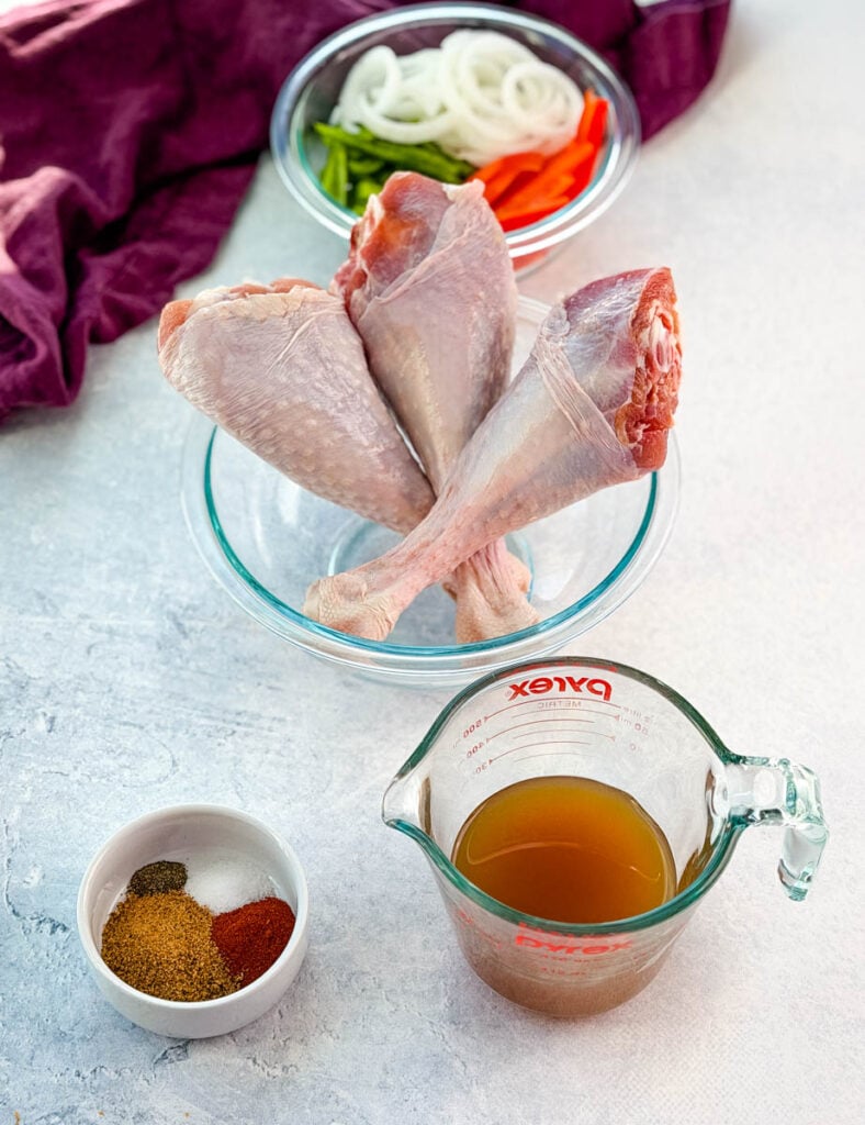2 raw turkey legs, chicken broth, and spices in separate bowls