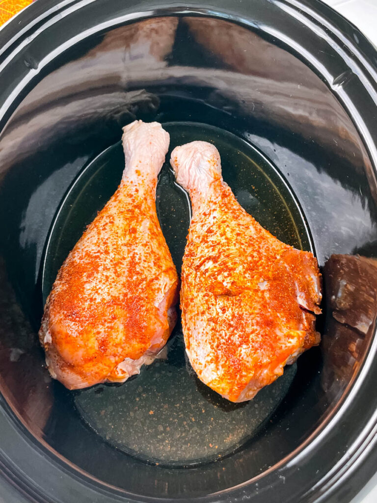 2 seasoned raw turkey legs in a Crockpot slow cooker