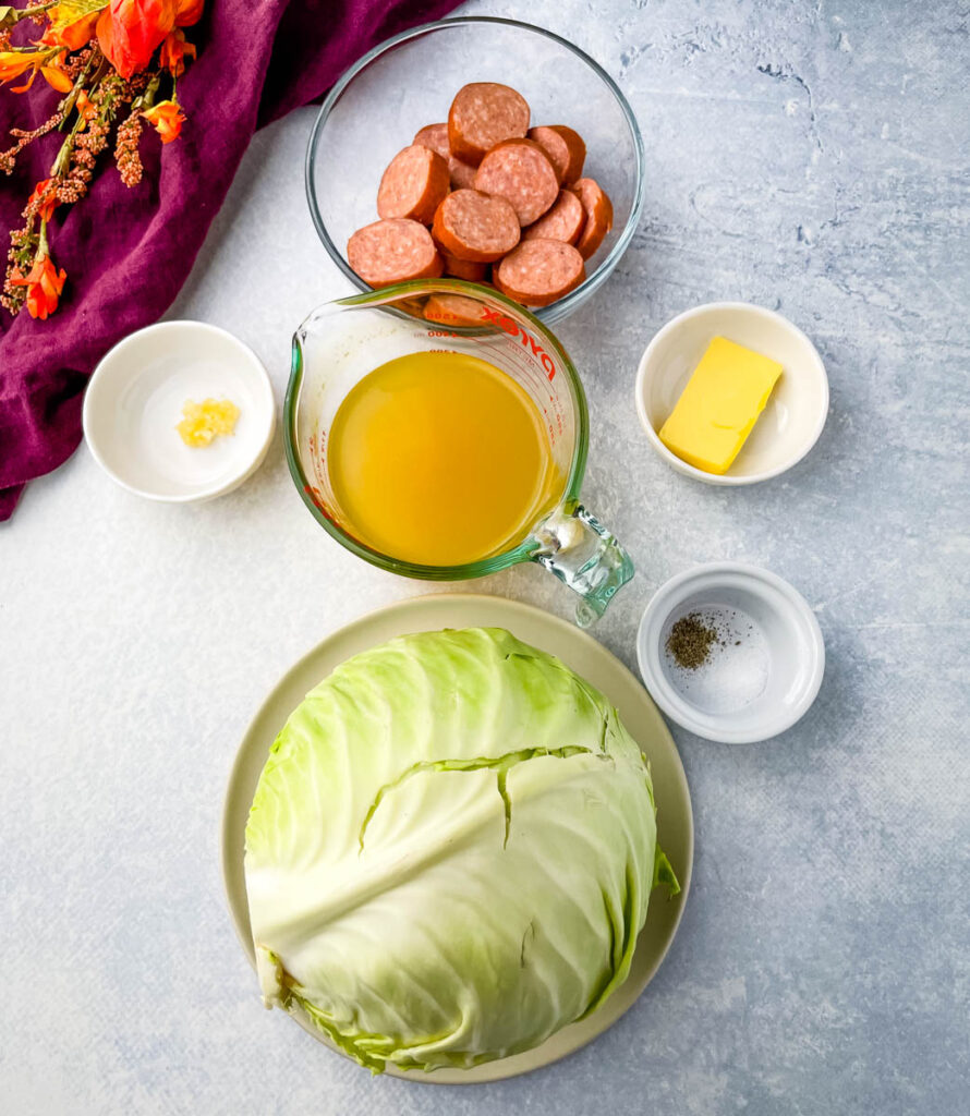 andouille sausage, garlic, butter, salt, pepper, and fresh cabbage on a flat surface