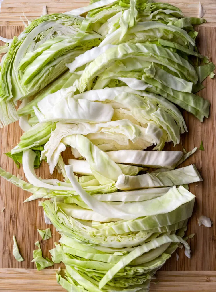 fresh cabbage sliced into strips on a cutting board