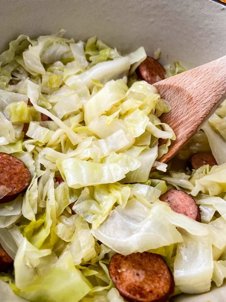 southern soul food cooked cabbage in a large pot with a wooden spoon