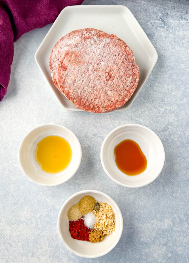 frozen burgers, liquid smoke, worcestershire sauce, and burger seasoning in separate bowls