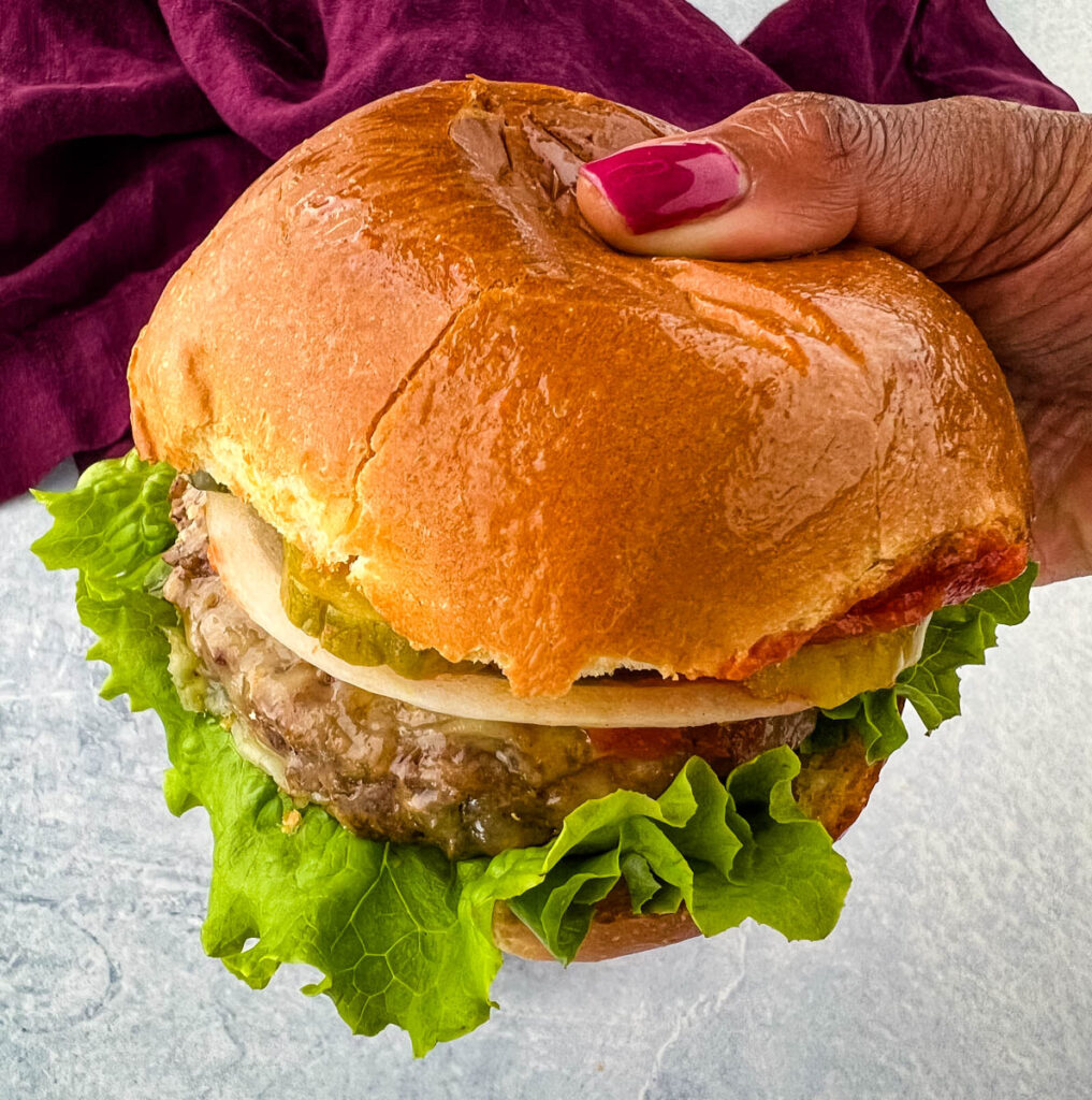 person holding air fryer cheeseburger